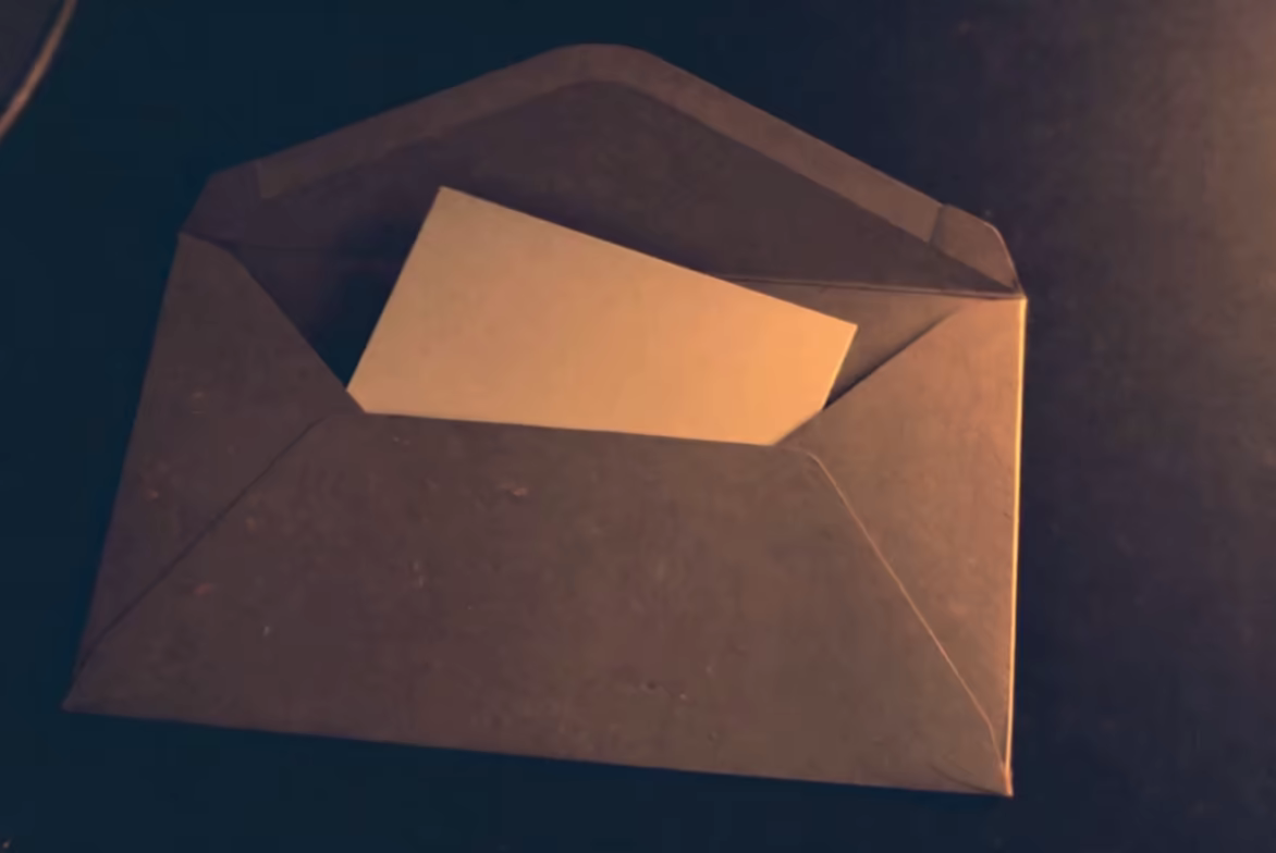 A blank card sliding out of a kraft envelope under warm lamp light
